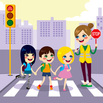 Three cute little children school students crossing street together with help from female teacher holding stop sign