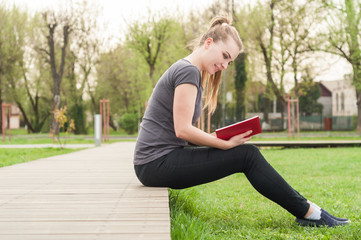 Fototapeta premium Happy young girl relaxing in the park and reading