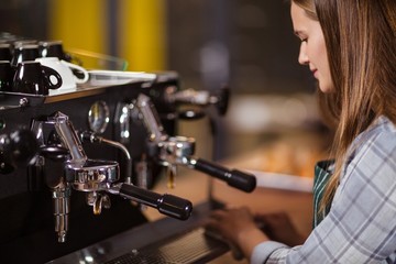 Smiling barista cleaning coffee machine