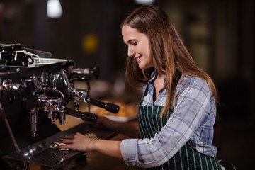 Fototapeta na wymiar Smiling barista cleaning coffee machine