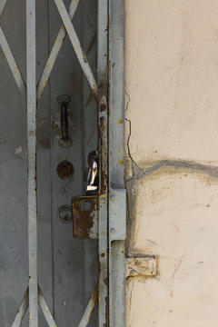 Ausschnitt einer alten verrosteten Gittertür mit Vorhängeschloss