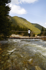 Beautiful woman tourist on a wooden bridge over a river