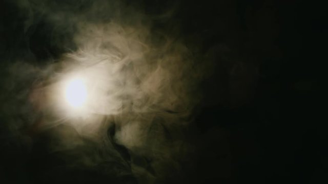 Spotlight included in the cloud of smoke on a black background