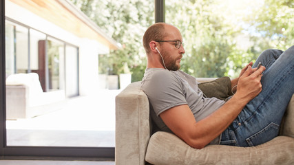 Man relaxing on sofa using digital tablet