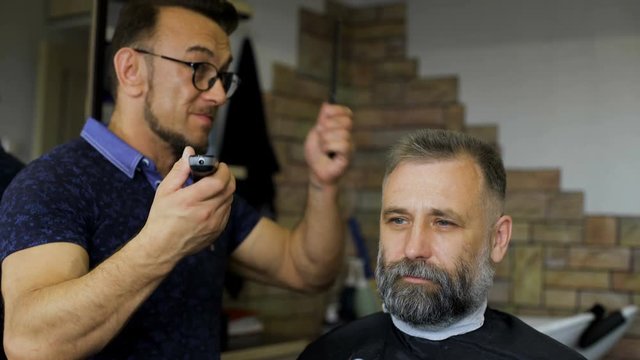 Cozy Barbershop, is engaged in a professional stylist haircut men aged. A respectable businessman in the client's chair. 