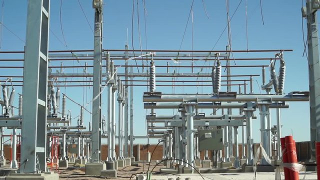 Long panning shot of an unfinished electrical substation under construction on the infrastructure grid used to generate, distribute and transmit electricity.