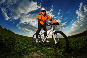 Fototapeta na wymiar biker in orange jersey riding on green summer field