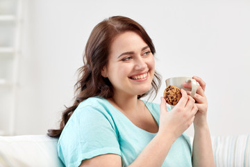 happy plus size woman with cup and cookie at home