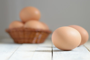 Some eggs in a basket on a white wooden table in a rustic kitchen. Empty copy space for editor's text.