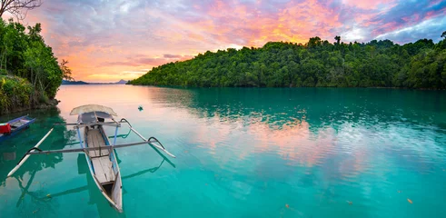 Foto op Canvas Breathtaking colorful sunset and traditional boat floating on scenic blue lagoon in the Togean (or Togian) Islands, Central Sulawesi, Indonesia, upgrowing travel destination. © fabio lamanna