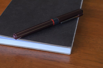 old note book and pen on wooden table .