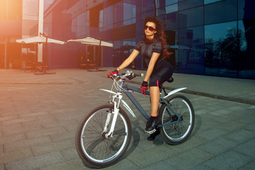 Fototapeta na wymiar cute brunette sports woman in sunglasses on a bicycle