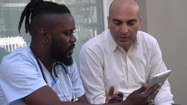 African american doctor showing patient medical documents using tablet computer. Side view
