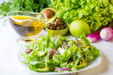 Green salad and ingredients lettuce, avocado, olives, oil, herb onion