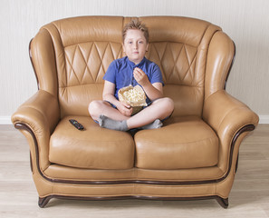 White boy sitting on the sofa and eating popcorn