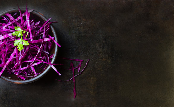 Shredded red cabbage in clay bowl. Background. Top view