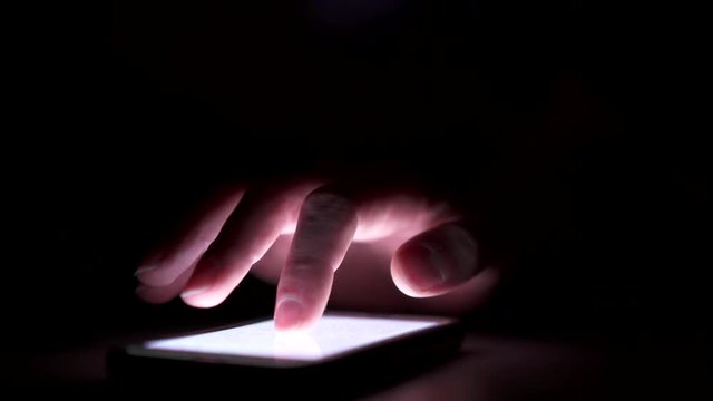 Touch screen pressed on smart phone in darkness.
