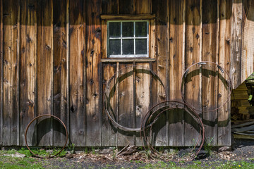 Vintage barrel hoops and small white window on weathered clapboard sided building