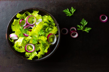 Salad lettuce, red onion, parsley black background. Top view