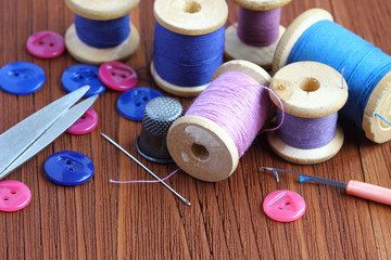 Sewing kit. Spools of thread and buttons on old wooden table.