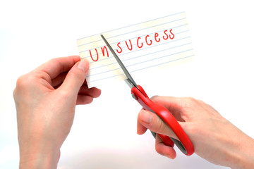 Female using scissors to remove the word unsuccess to read succe
