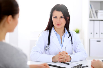 Fototapeta premium Brunette female doctor talking to patient in the hospital