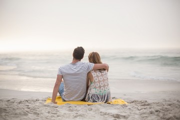 Rear view of couple sitting on the beach