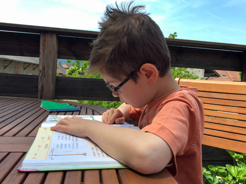 Enfant faisant ses devoirs pour l'&eacute;cole, lisant sa le&ccedil;on de lecture