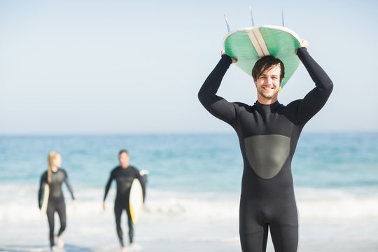 Happy Man In Wetsuit Carrying Surfboard Over Head