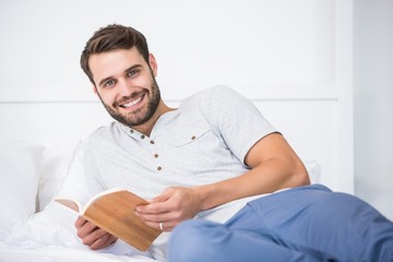 Man holding book on bed at home