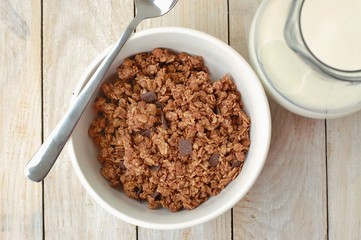 Chocolate musli with milk in the glass jug on the wooden background