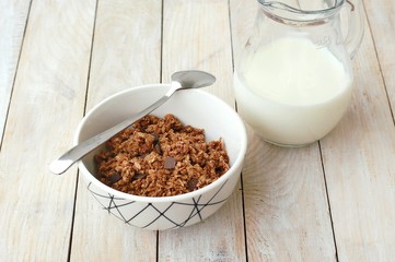 Chocolate musli with milk in the glass jug on the wooden background