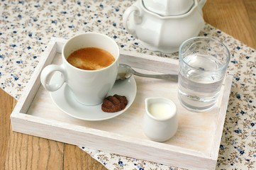 Espresso in the cup with milk, biscuit and sugar basin