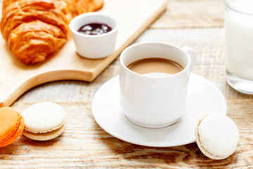 sweet breakfast with coffee, macaroons and croissants on wooden table