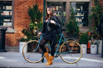 Obraz premium Fashionable woman with a bicycle in the city wearing traveler backpack
