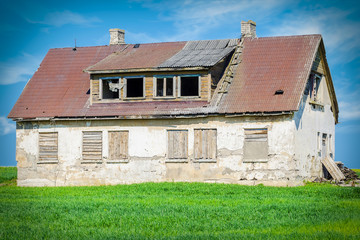 Fototapeta na wymiar Old abandoned damaged house on grass field