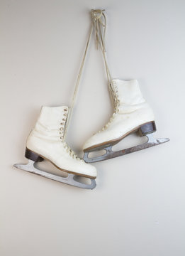 Old white ice skates hanging on the wall