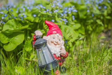 garden gnome - lamp standing on the grass in the garden amid the flowers