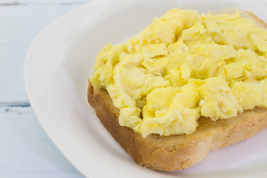 Scrambled eggs on toast on blue table
