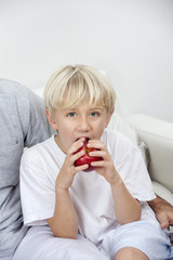 Little blonde boy playing and eating an apple