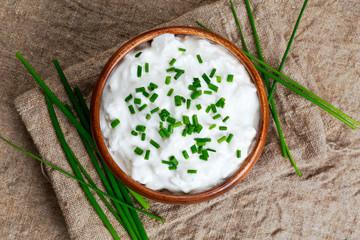 Cottage cheese with chives in wooden bowl. background