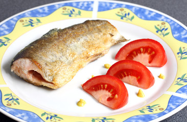 decorated plate with fried fish: river trout and tomatoes on white background