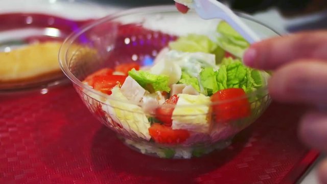 Adding souse and seasoning mixing caesar chicken salad in transparent fast food pack 