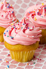 cropped image of strawberry cupcake with sugar icing and sprinkles.