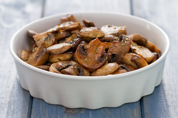 fried mushrooms on white dish on blue wooden background