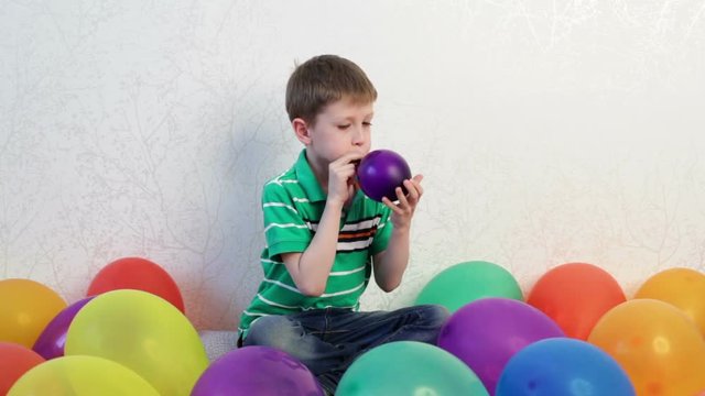 A little boy inflates a purple balloon. Then the ball is blown off.