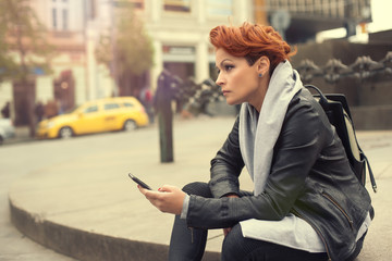 Fototapeta premium Young woman using mobile on the street / Young woman using mobile telephone on the street