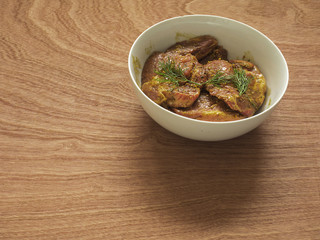 Bowl with marinated pork on a wooden surface.