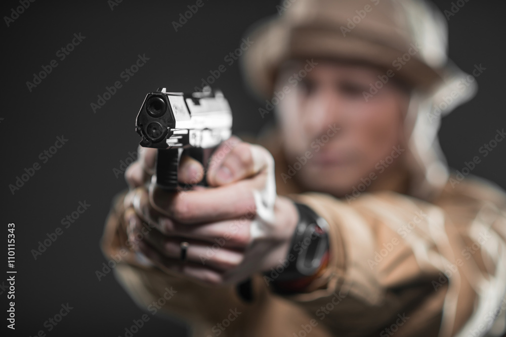 Wall mural Soldier with a gun takes aim on dark background