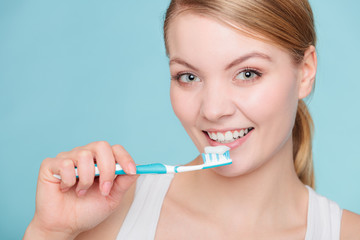 woman holds toothbrush with toothpaste cleaning teeth